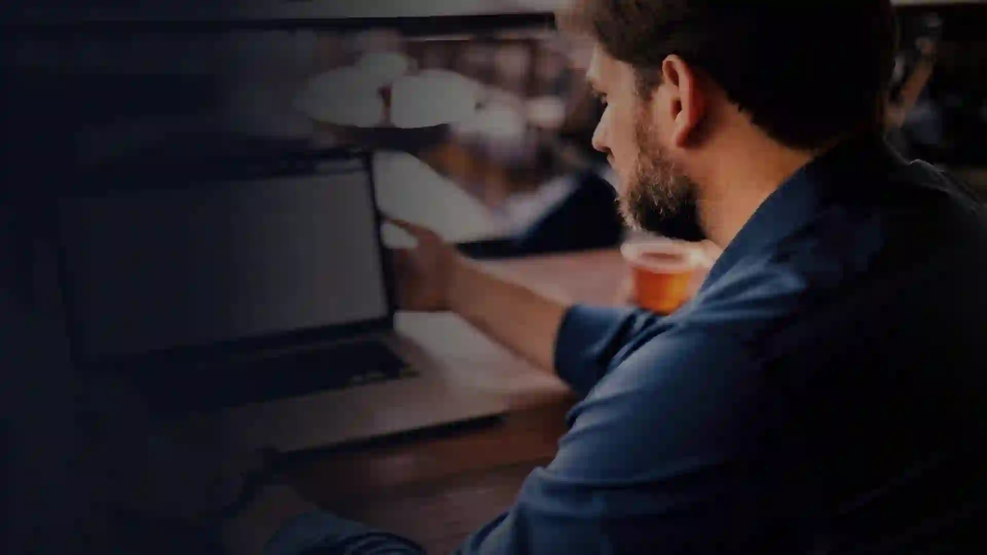 Paul David Thompson working at a laptop in a quiet coffee shop, side view.